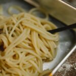 cooked spaghetti and fork placed in steel bowl