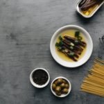 delicious anchovies with oil and onion leeks beside a bowl of pepper and olives