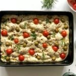raw focaccia with cherry tomatoes green olives and herbs