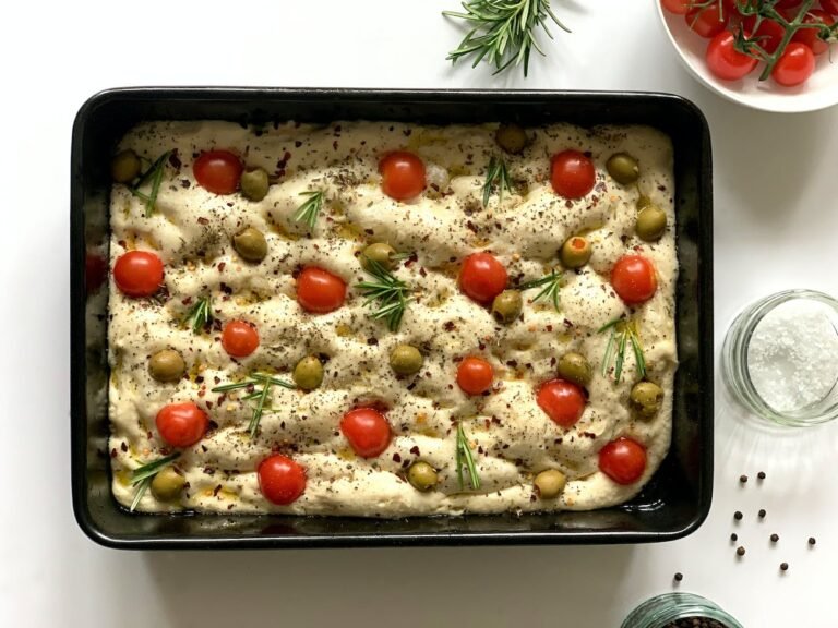 raw focaccia with cherry tomatoes green olives and herbs