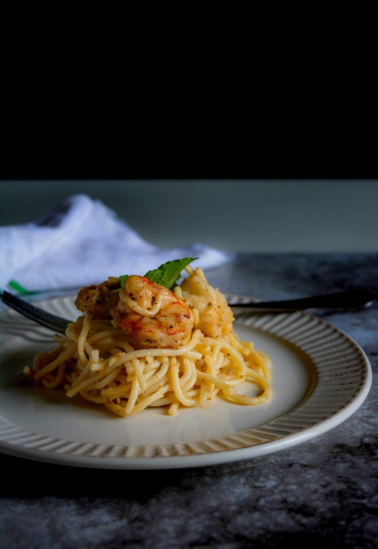 Piatto di spaghetti ai gamberi con crema al limone poggiato su un tavolo da pranzo